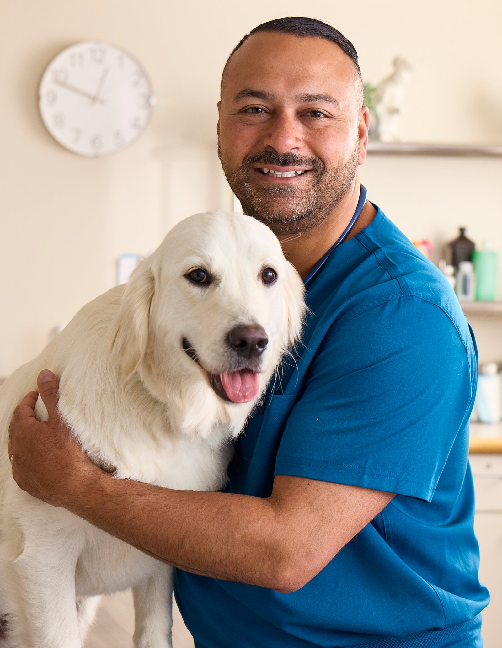 Dr. James Bascharon in blue scrubs with golden retriever