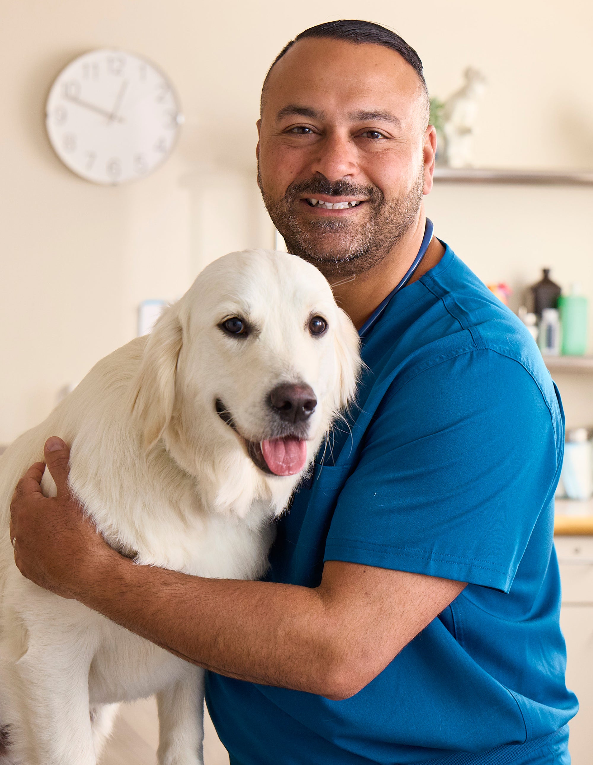 Dr. James Bascharon in blue scrubs with golden retriever